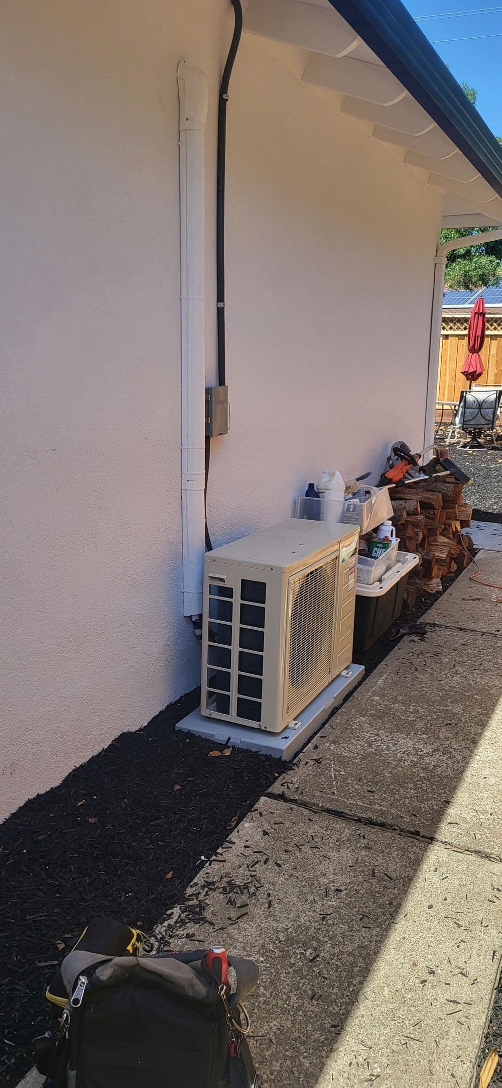 Air conditioning unit installed beside a house, with tools and materials in the background.