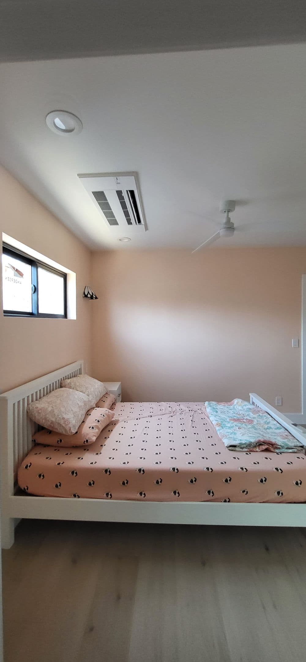 Cozy bedroom with light peach walls, a double bed, and a ceiling fan.